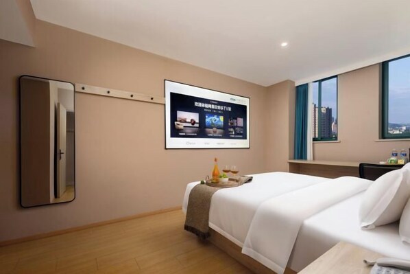 A hotel room with a bed, a TV mounted on the wall, a window with a city view, and a wooden floor. - Yuejia Hotel (Xuancheng Jingtingshan Branch) (Xuancheng)