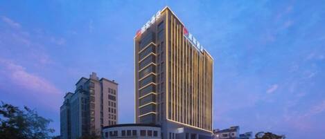 A modern hotel with a prominent vertical design, multiple floors, and a well-lit entrance.
