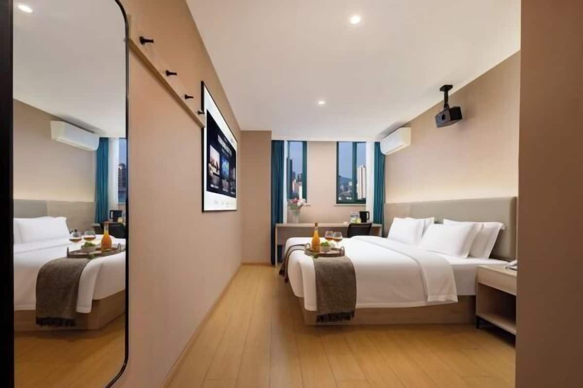 A modern hotel room with two beds, a desk, and a large mirror.
