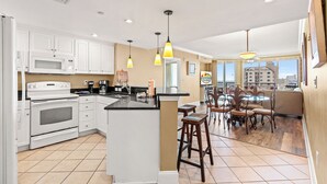 A modern kitchen with white cabinets, a central island, and pendant lighting.