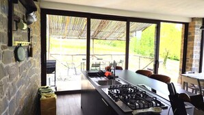 A modern kitchen with a large island, a gas stove, and a view of an outdoor patio area. - TUSCANY DETACHED HOUSE INCREDIBLE PANORAMA, LARGE GARDEN 5 MIN FROM AREZZO (Toscana)