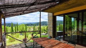 A covered patio with a table and chairs, a view of the countryside, and a stone wall. - TUSCANY DETACHED HOUSE INCREDIBLE PANORAMA, LARGE GARDEN 5 MIN FROM AREZZO (Toscana)
