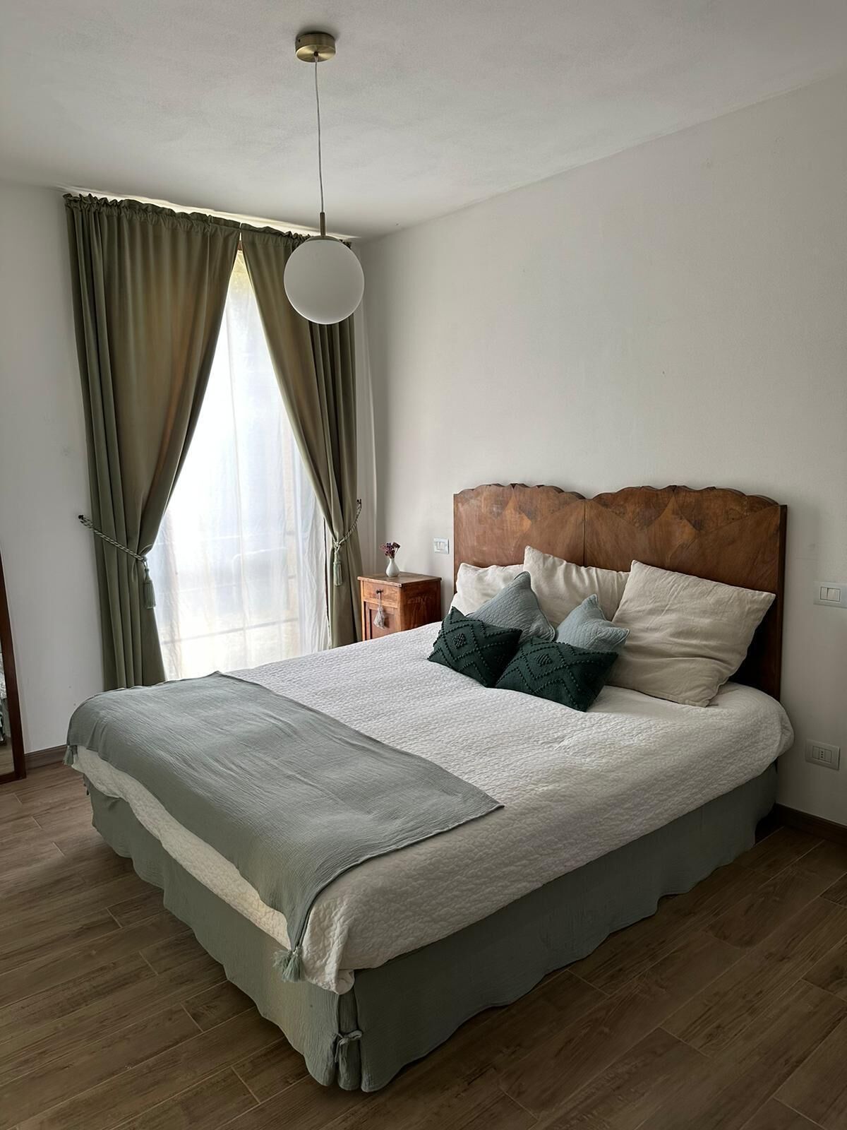 Une chambre à coucher avec un grand lit, une tête de lit en bois et une table de chevet avec une lampe.