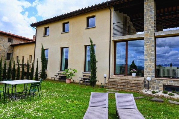 A two-story house with a stone facade, large windows, and a small garden with a table and chairs. - TUSCANY DETACHED HOUSE INCREDIBLE PANORAMA, LARGE GARDEN 5 MIN FROM AREZZO (Toscana)
