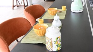 A modern kitchen with a long countertop, a coffee maker, and a kettle. There are orange chairs and a dining table with yellow cups and bowls. - TUSCANY DETACHED HOUSE INCREDIBLE PANORAMA, LARGE GARDEN 5 MIN FROM AREZZO (Toscana)