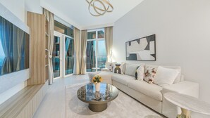 A modern living room with a glass coffee table, a sofa, and a large window offering a view. - Premium 2BR Apt Home Fully Furnished (Dubai)