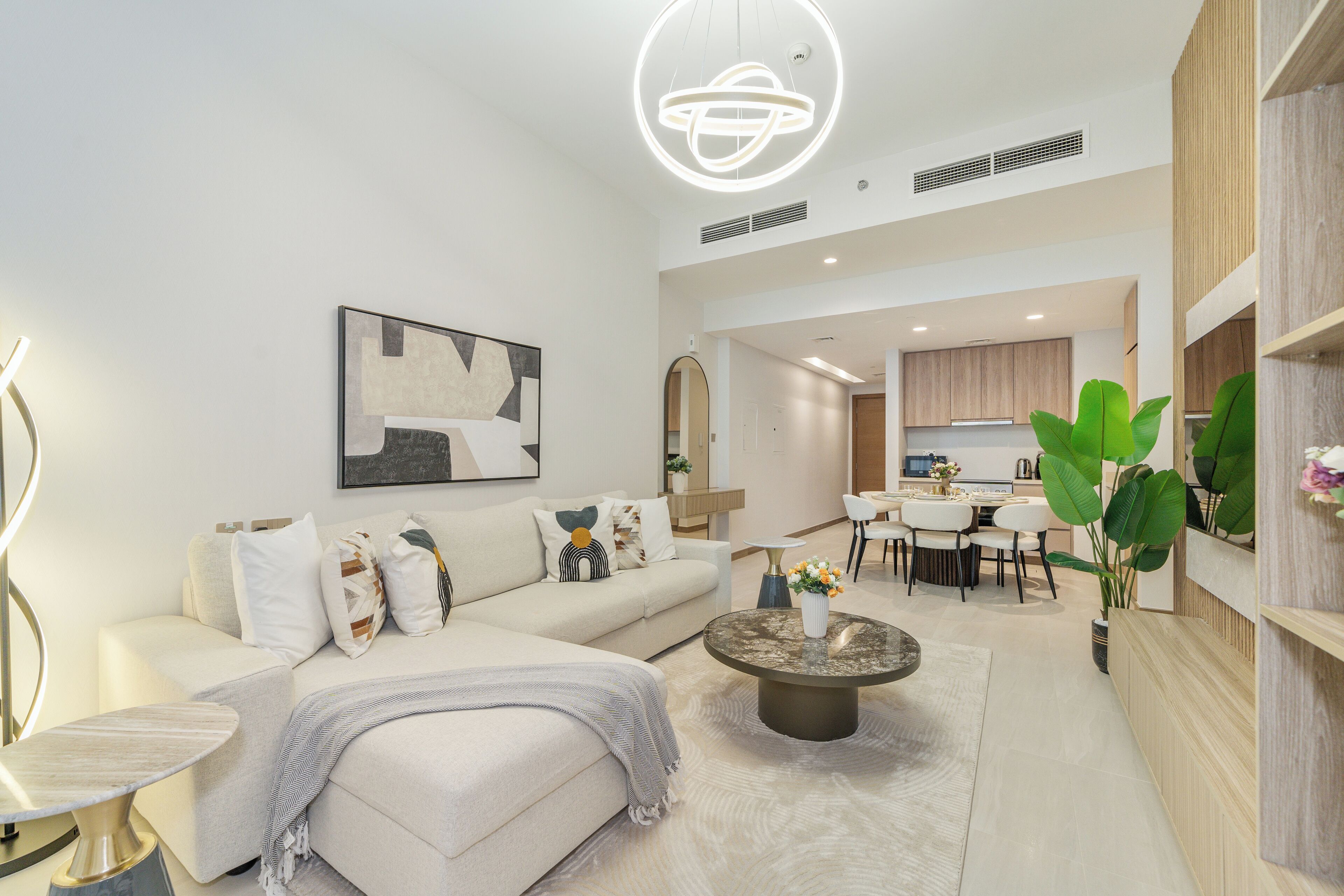 A modern living room with a sofa, coffee table, and a dining area with chairs and a table.