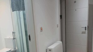A bathroom with a toilet, a glass shower enclosure, and a white radiator. - Seaview Loft 20 Portrush (Portrush)