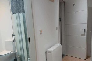 A bathroom with a toilet, a glass shower enclosure, and a white radiator.