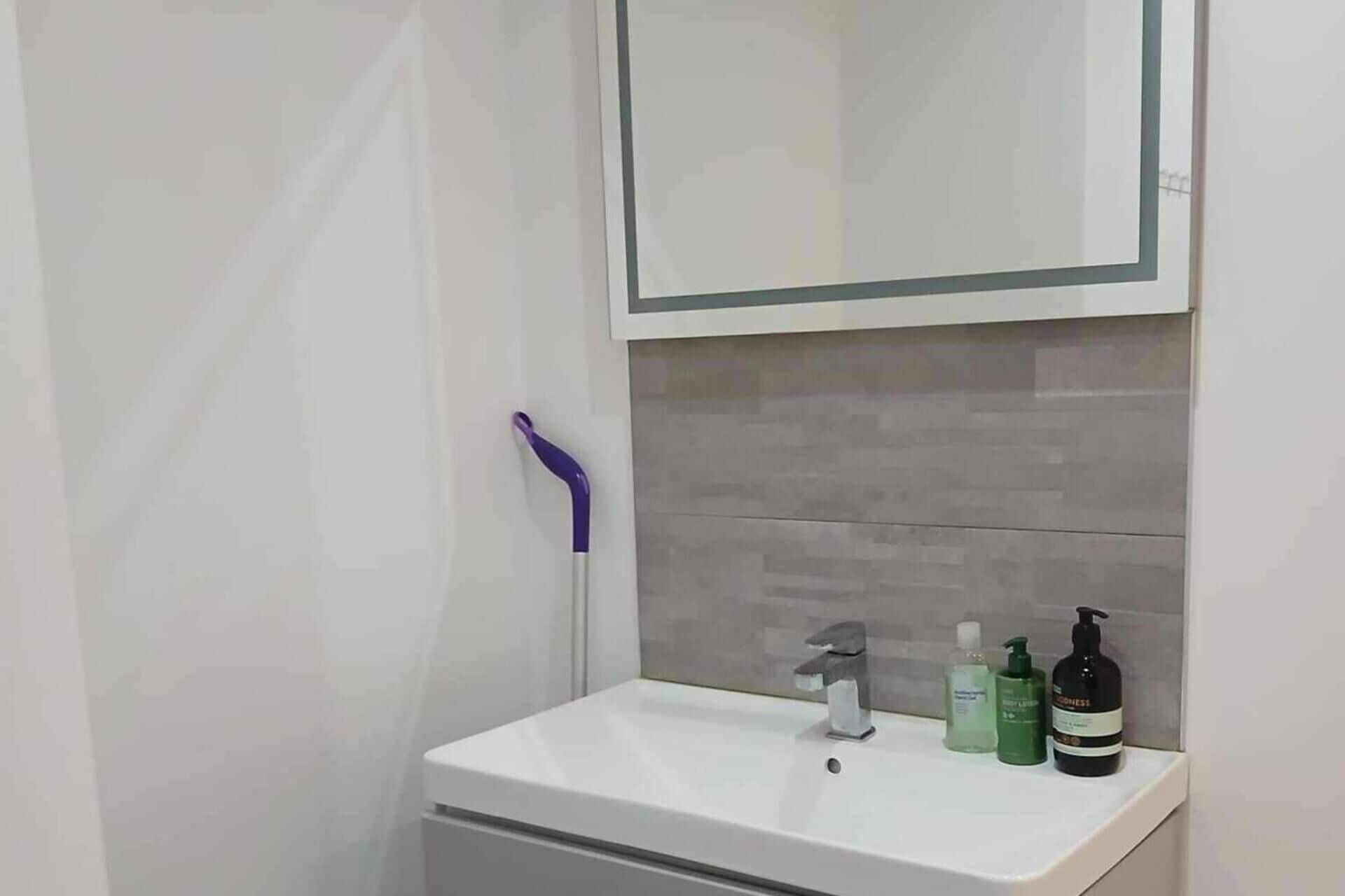 A bathroom with a white sink, a mirror, and a shower area.