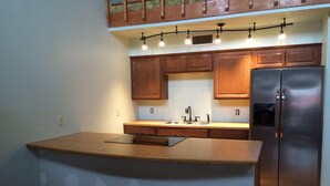 Eine Küche mit Holzschränken, einem Edelstahlkühlschrank und einer Holzausziehtafel.