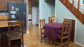 Ein Essbereich mit Holztisch und Stühlen, einem Kühlschrank und einer Treppe mit Holzbalkonen.