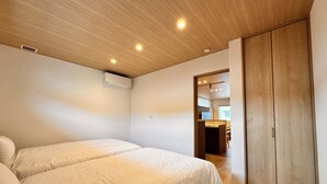 A bedroom with two beds, a wooden ceiling, and a wardrobe. - AOI SUITE TAKAYAMA (Takayama)