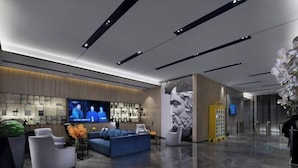 A modern lobby with a flat-screen TV, seating area, and a large wall mural. - Echarm Hotel (Guangzhou Beijing Road Pedestrian Street Tianzi Pier) (Guangzhou)