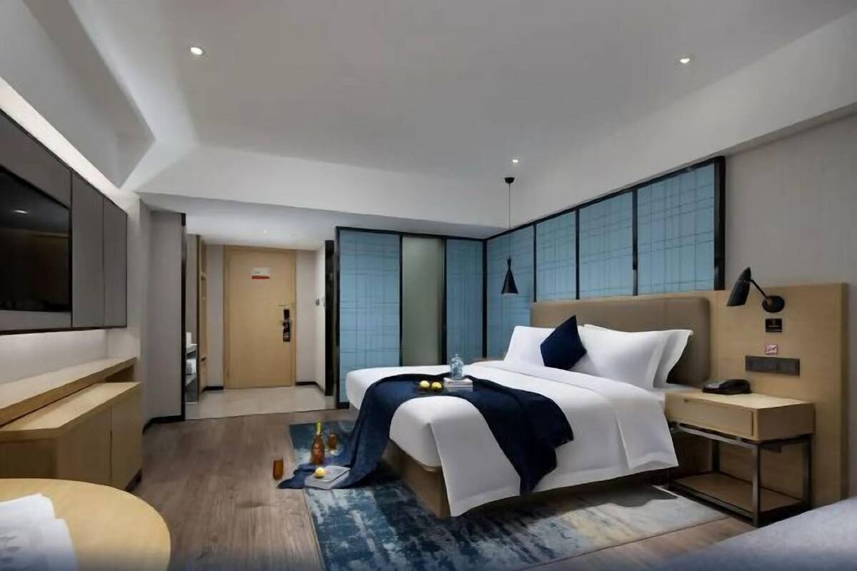 A modern hotel room with a large bed, bedside tables, a desk, and a TV.