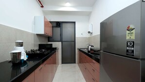A kitchen with stainless steel appliances, a microwave, a kettle, and a toaster. - 3 BHK Urban Suite ( Gagal Home) (Mumbai)