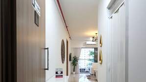 A hotel hallway with a reception desk, a wooden door, and a view into a living area with a sofa and a plant. - 3 BHK Urban Suite ( Gagal Home) (Mumbai)