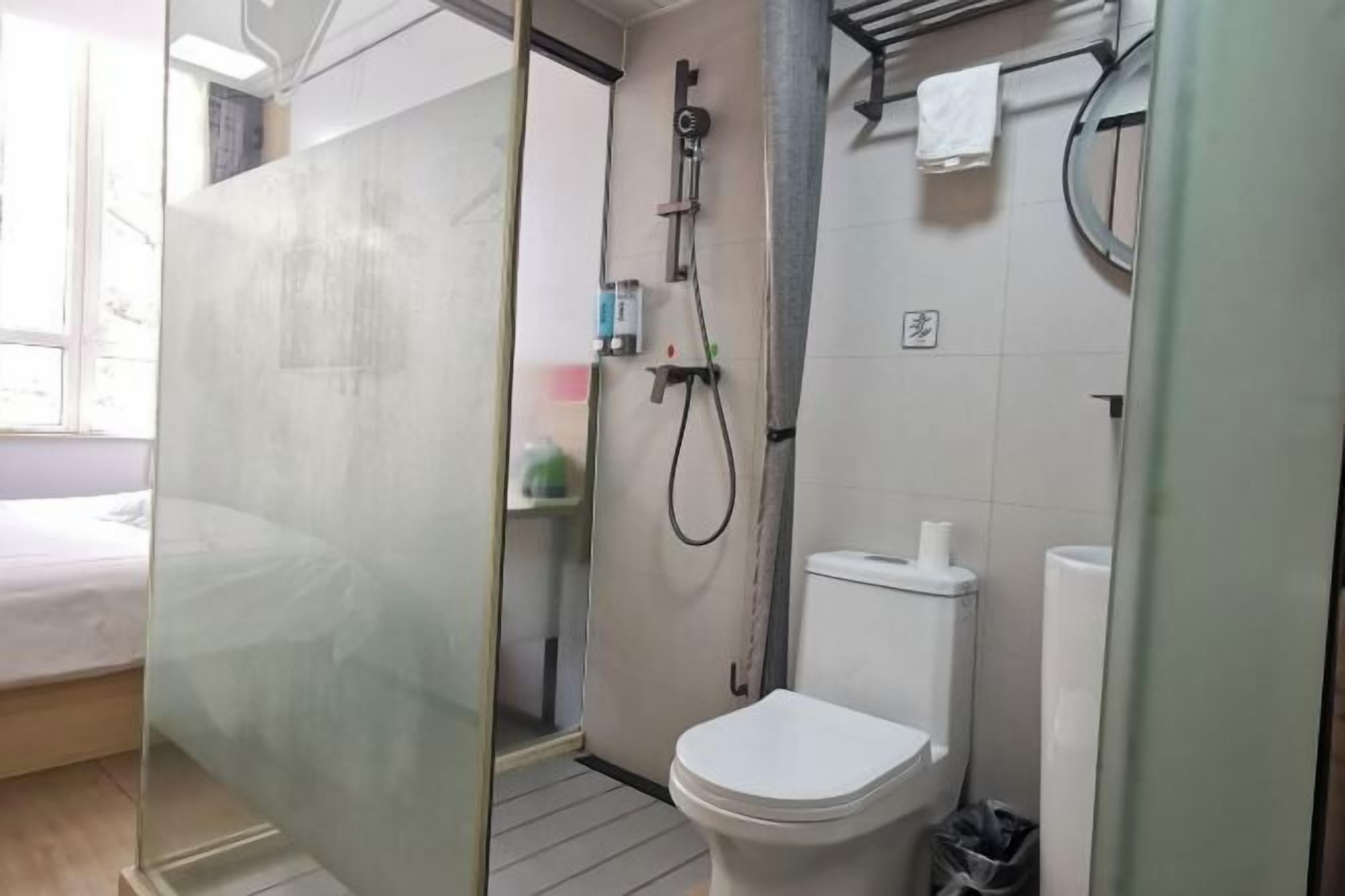 Ein Badezimmer mit Glasabtrennung, Toilette, Dusche und Handtuchhalter.