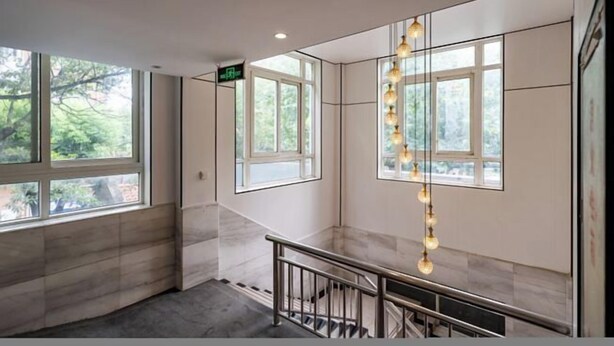 Un interior moderno con ventanas amplias, una escalera y un colgador de luz.