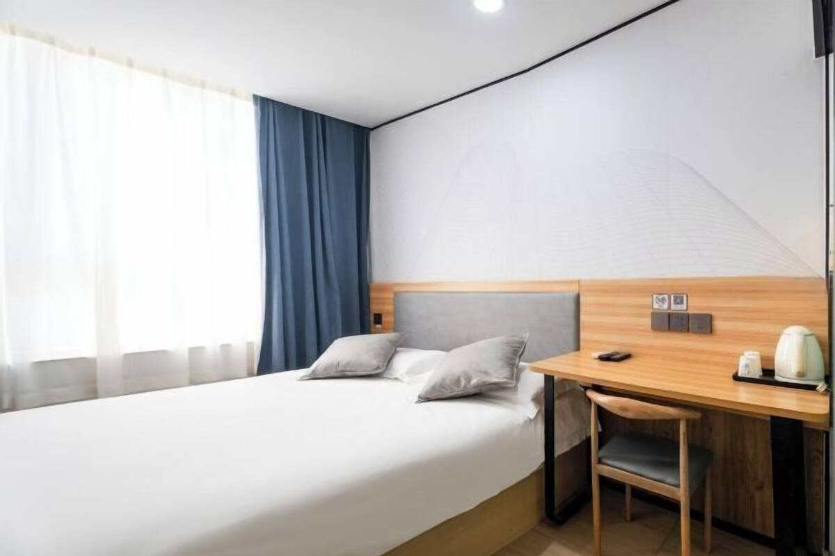 A hotel room with a bed, a desk, and a chair.