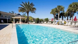 A swimming pool with clear water, surrounded by lounge chairs and palm trees. - 2335 Amazing 5BD Family Townhome Close to Disney (Kissimmee)