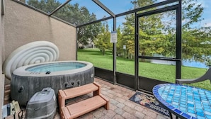 A covered patio area with a hot tub, wooden steps, and a view of a lake. - 2335 Amazing 5BD Family Townhome Close to Disney (Kissimmee)