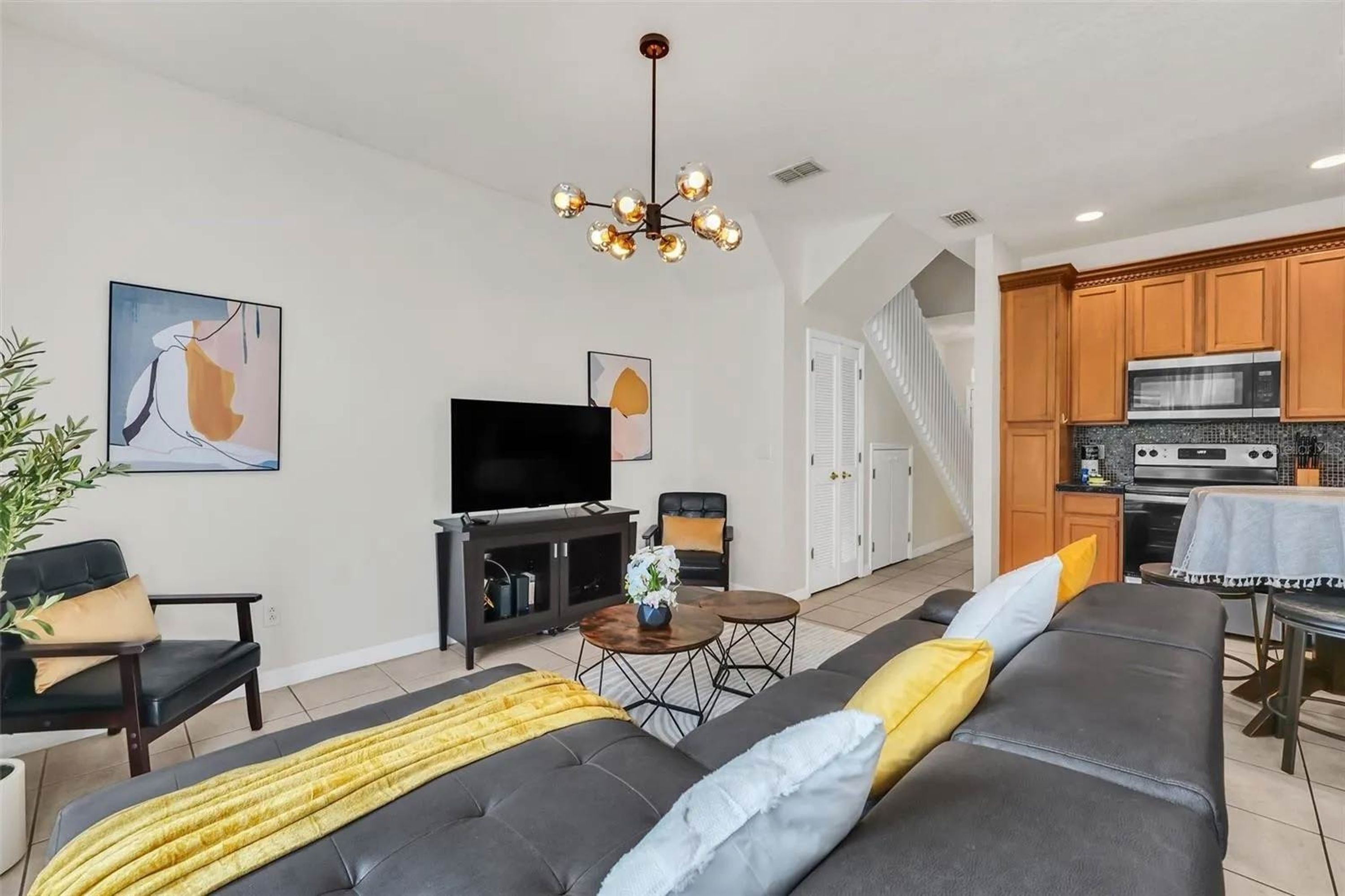 A modern living room with a sofa, TV, and dining area.