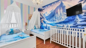 A child's bedroom with a bed, a white crib, a mural of a winter landscape, and a chandelier. - 2335 Amazing 5BD Family Townhome Close to Disney (Kissimmee)