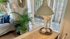 Una mesa de madera para comer con una lámpara, una planta en maceta y objetos decorativos.