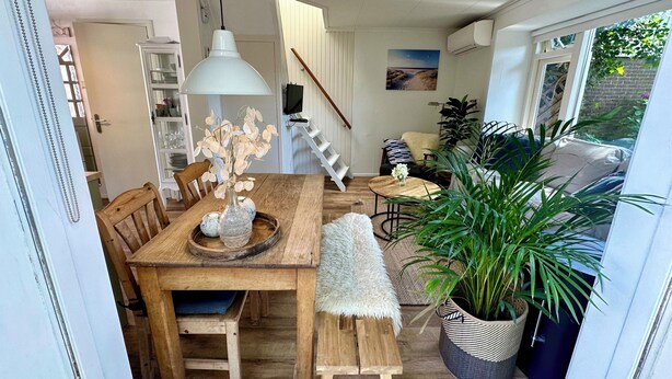 Un comedor acogedor con mesa de madera, banco y lámpara colgante.