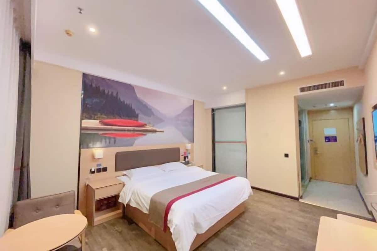 Camera d'albergo con un letto, un comodino e una TV a parete.