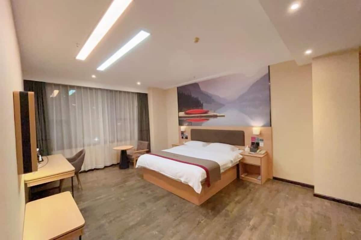 Una camera d'albergo moderna con un letto grande, comodini, una scrivania e una sedia.