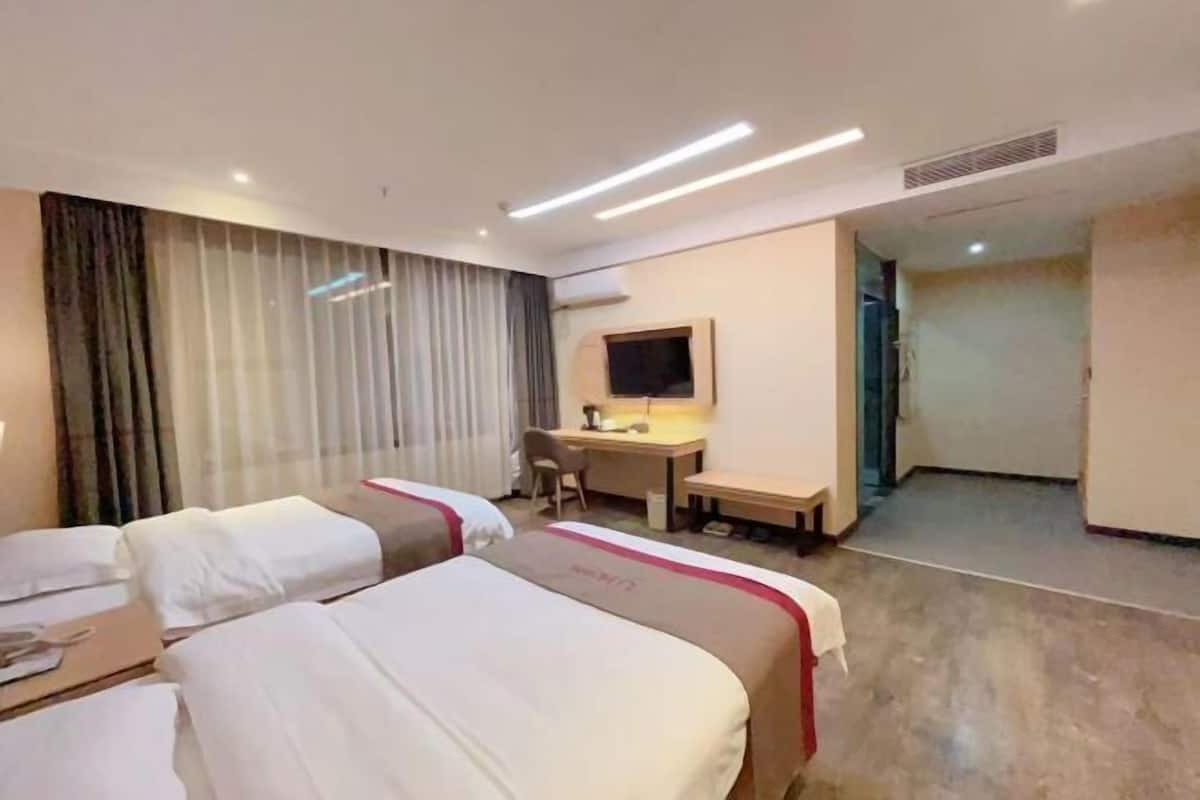 Una camera d'albergo con due letti, una scrivania, una sedia e una televisione.