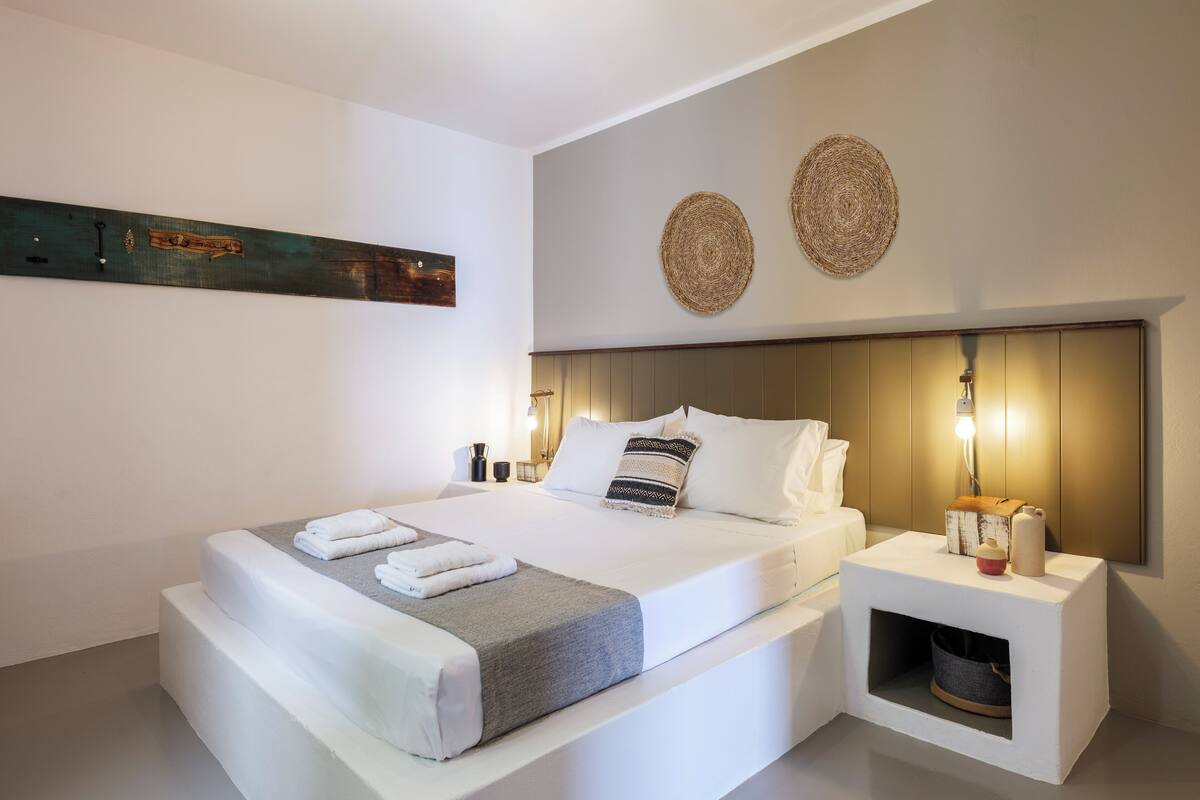 Un dormitorio moderno con una cama grande, mesitas de noche, una lámpara de pared y una cama pequeña para mascotas.