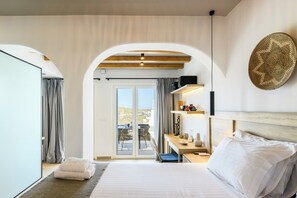 A modern hotel room with a large bed, a balcony with a view, and a wooden ceiling. - Mykonist Merchia Beach Villas & Suites (Mykonos)