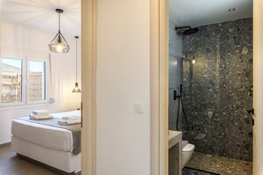 A hotel room with a bed, a window, a shower, and a bathroom. - Mykonist Merchia Beach Villas & Suites (Mykonos)
