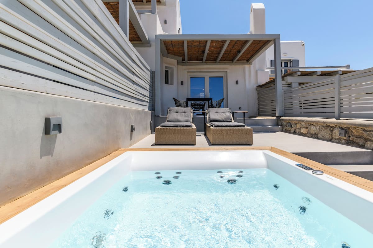Un área de piscina en la azotea con dos sillas de descanso y un jacuzzi.