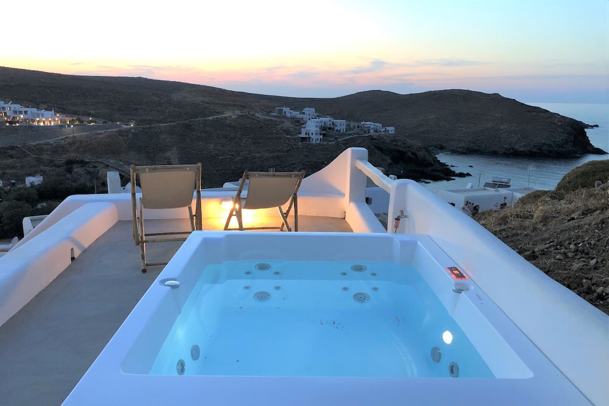 Un jacuzzi con dos sillas, con vistas a un paisaje costero y edificios al fondo.
