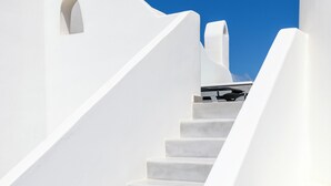 A white staircase leading up to a building with a clear blue sky in the background. - Mykonist Merchia Beach Villas & Suites (Mykonos)