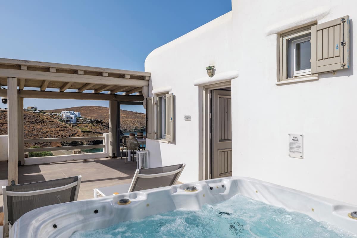 Zona de spa con jacuzzi, mobiliario exterior y vista a una colina.
