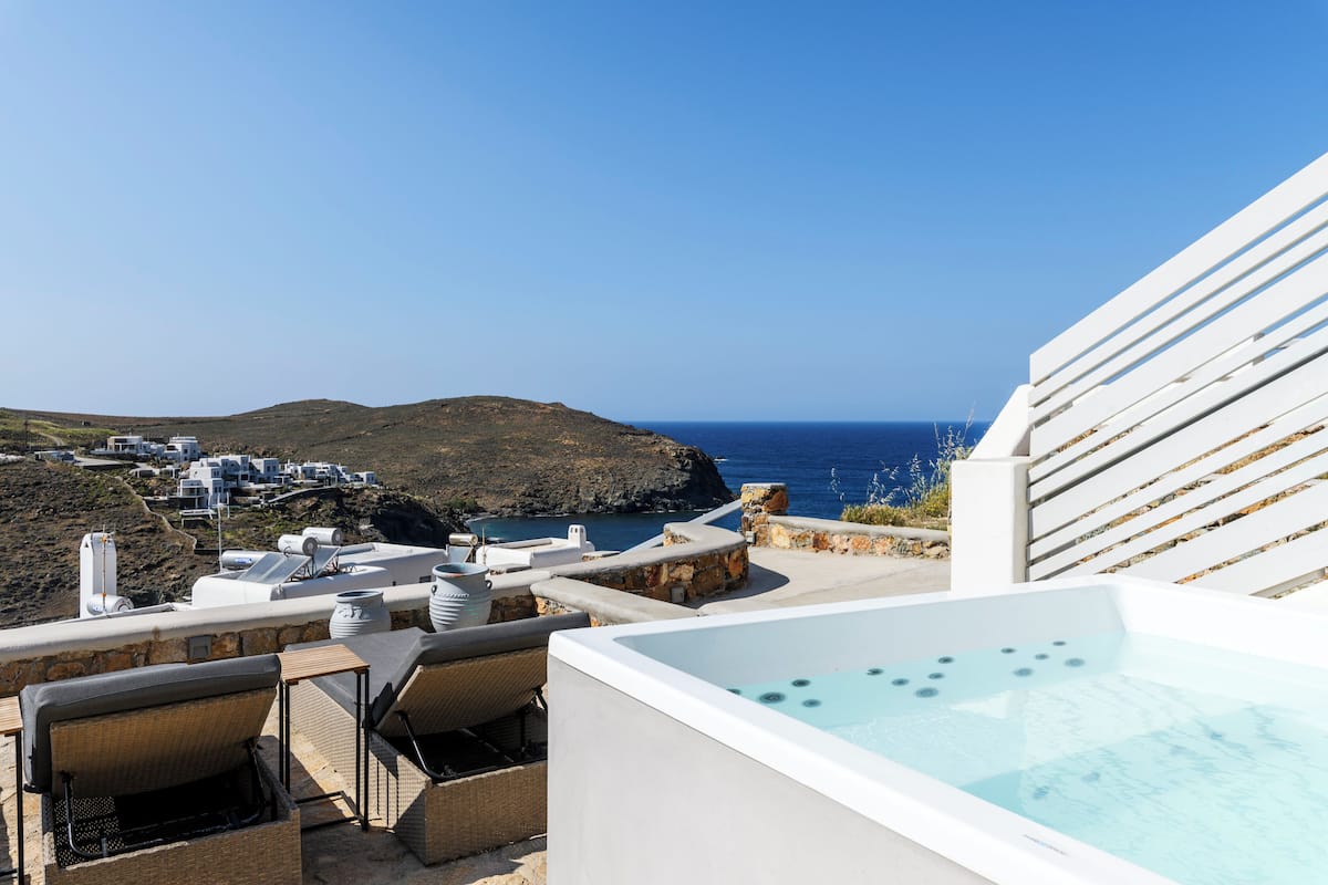Una terraza en la azotea con jacuzzi, sillones de descanso y vistas al mar y las colinas.