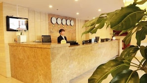 A reception desk with a digital screen, a clock, and a plant. - 1896 Hotel (Dalian Railway Station Russian Style Street Store) (Dalian)