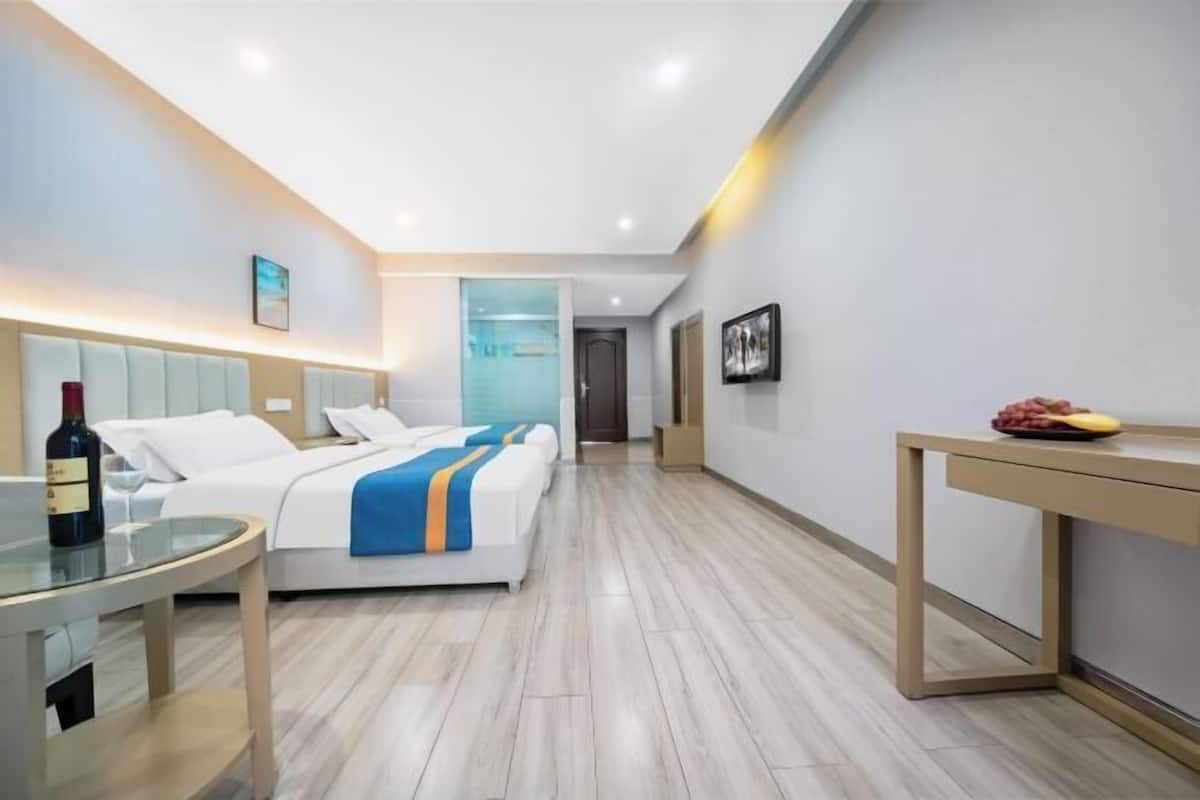 Een hotelkamer met een bed, nachtkastje en een tafeltje met een fles en glazen.