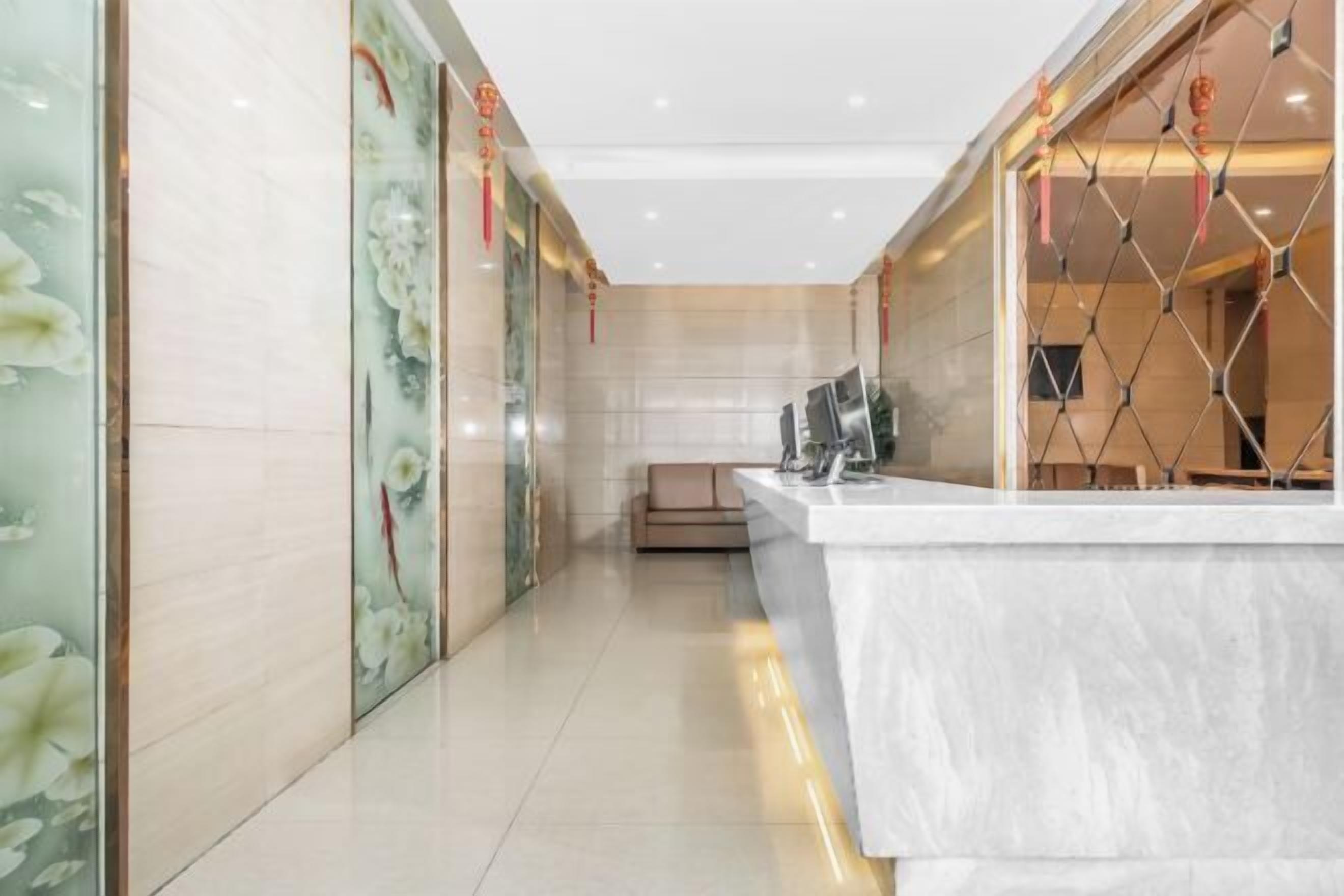 A modern hotel lobby with a reception desk, a sofa, and decorative elements.