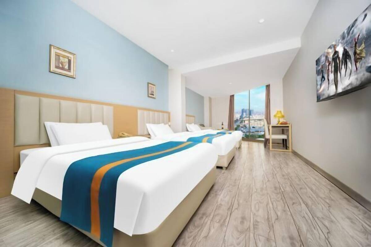 Een hotelkamer met een groot bed, een bureau en uitzicht op een stadsbeeld.
