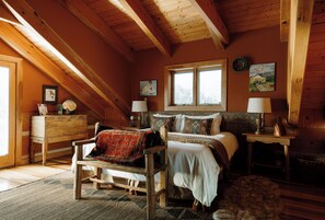A cozy bedroom with a wooden ceiling, a large bed with a red blanket, two bedside tables with lamps, and a window with a view. - Perfect for your Large Group! Amazing Outdoors-3rd nt FREE thru December! (Valdez)