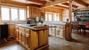 A spacious kitchen with wooden cabinets, a large island, and a dining area with a table and chairs. - Perfect for your Large Group!  Amazing Outdoors-4th nt. FREE in August! (Valdez)