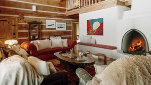 A cozy log cabin interior with a fireplace, wooden beams, a red sofa, and a loft area. - Perfect for your Large Group!  Amazing Outdoors-4th nt. FREE in August! (Valdez)