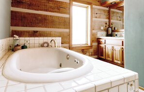 A bathroom with a large bathtub, wooden wall paneling, a window, and a wooden vanity with drawers. - Perfect for your Large Group! Amazing Outdoors-3rd nt FREE thru December! (Valdez)
