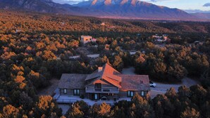 A large, modern house with a sloped roof, surrounded by dense forest and mountains in the background. - Perfect for your Large Group!  Amazing Outdoors-4th nt. FREE in August! (Valdez)